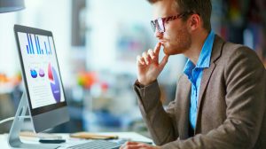 Young pensive businessman in eyeglasses working in office